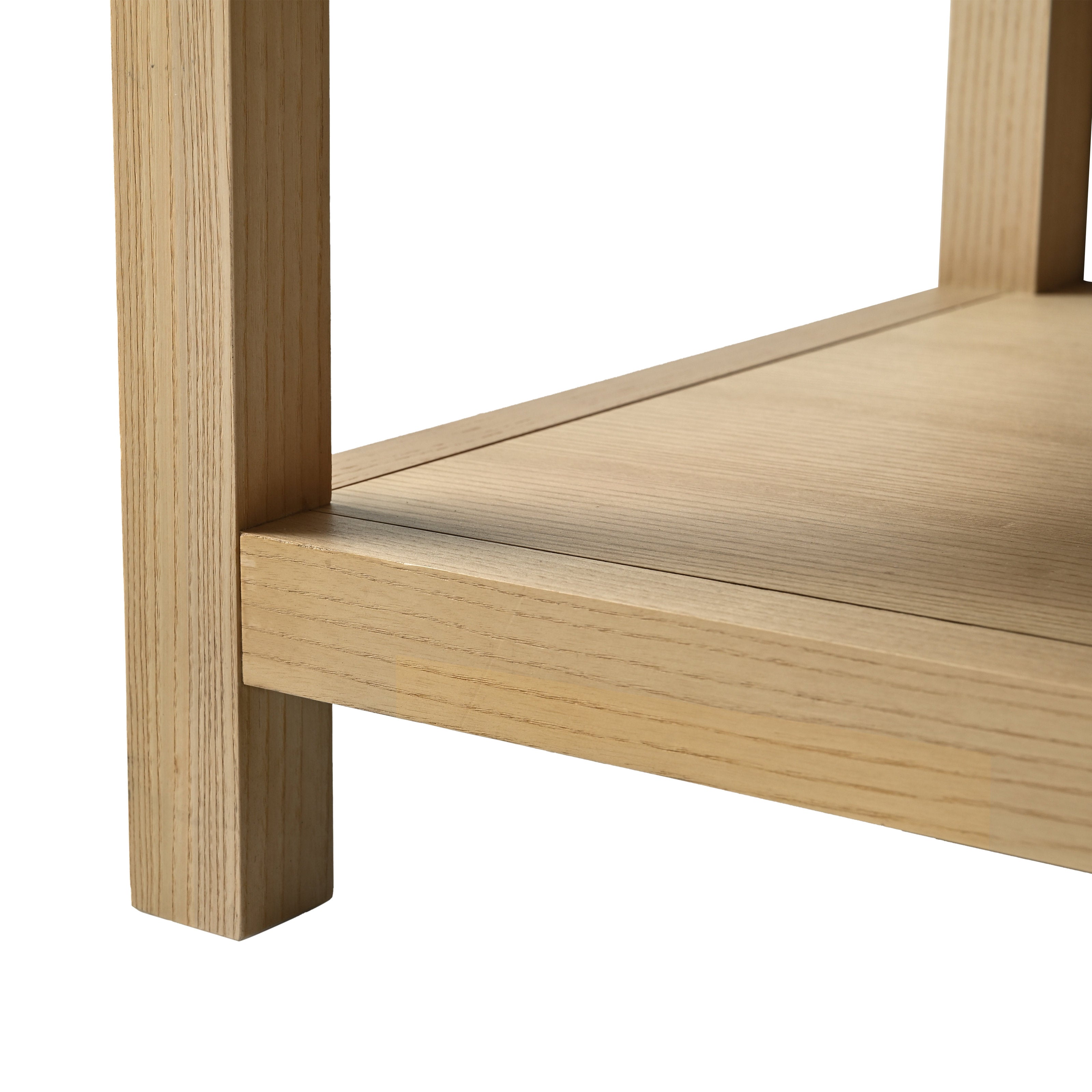 Close-up of a light solid-wood vanity leg and lower shelf corner showing natural grain, smooth edge joinery and a mitered shelf seam in a natural wood finish.