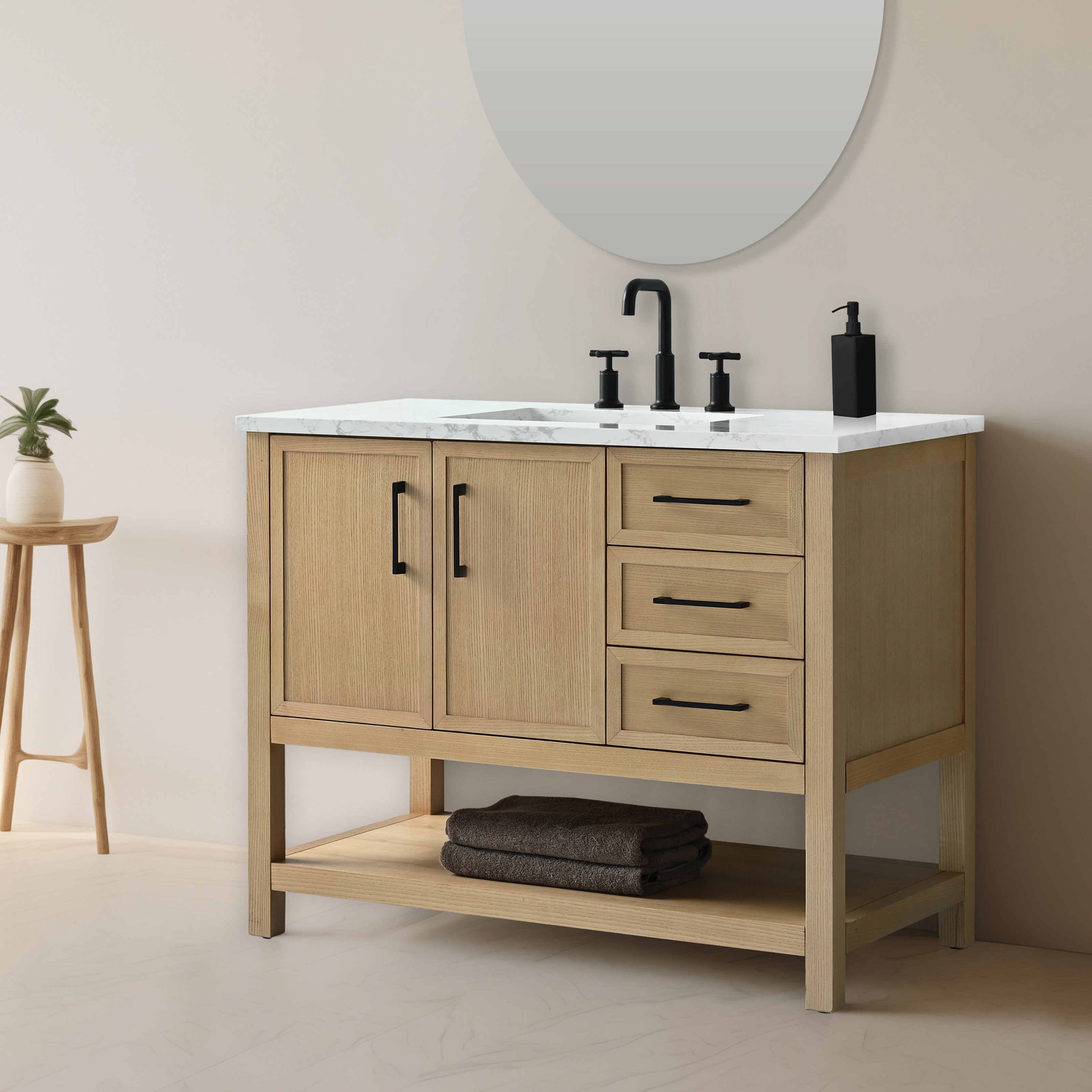 Modern 42-inch solid wood bathroom vanity with white stone marble top, matte black faucet and hardware, two-door cabinet, three drawers and an open lower shelf with folded towels, shown with round mirror and small plant.
