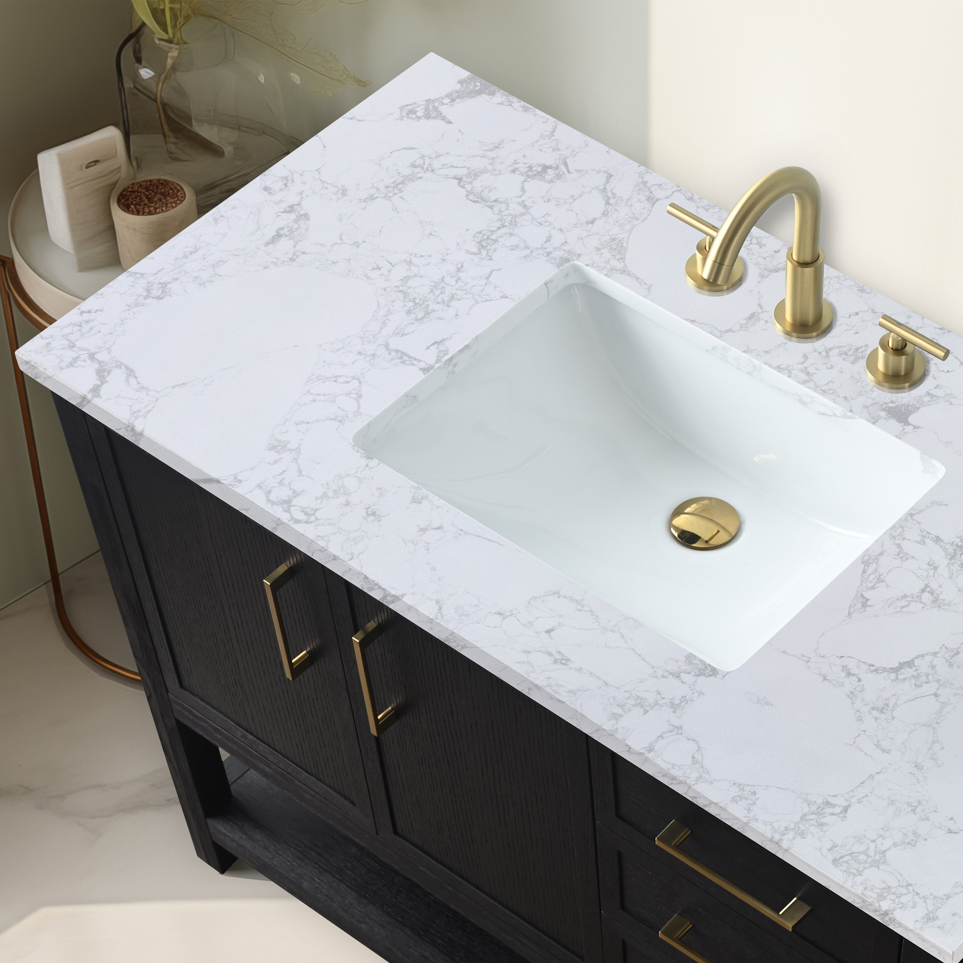 Top-down view of a black solid wood bathroom vanity with a white marbled stone countertop, rectangular undermount ceramic sink and matching brass faucet, drain and cabinet pulls.