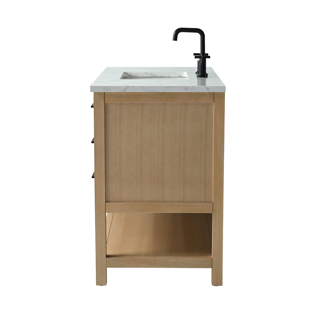 Side view of a modern single-sink bathroom vanity with a stone marble-look top and inset ceramic basin, solid light wood frame, open lower shelf and a matte black faucet.