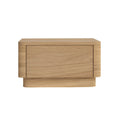 Front-facing solid oak nightstand in a natural finish with a single flush drawer, rounded corners and a recessed plinth base, shown on a white background in a modern minimalist style.