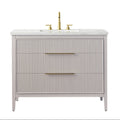 Front view of a modern single-sink solid wood bathroom vanity in stone finish with vertical fluted drawer fronts, white stone countertop with integrated ceramic sink, and gold-brass faucet with matching slim horizontal pulls.