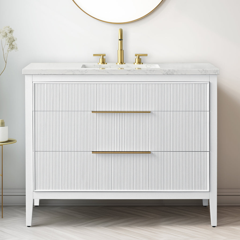 Freestanding modern 42-inch single-sink bathroom vanity in white solid wood with a stone marble top, integrated rectangular ceramic basin, brass widespread faucet and slim brass handles on two ribbed-front drawers.