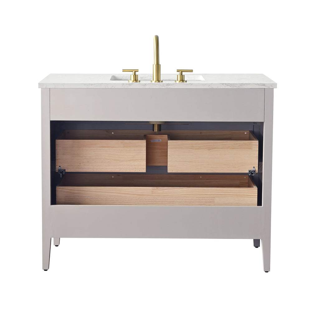 Front view of a modern single-sink bathroom vanity with a white stone countertop, taupe solid-wood cabinet, brass faucet, and exposed light-wood drawer boxes.