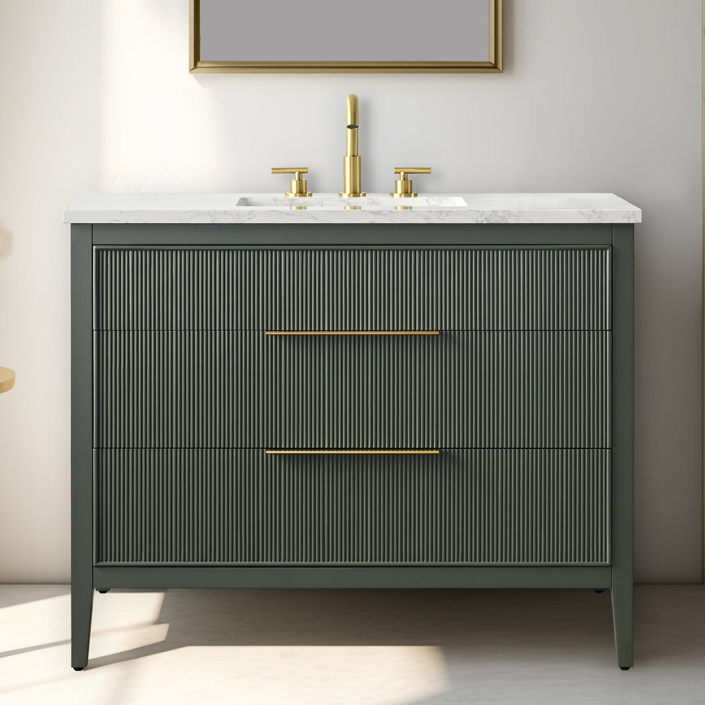 Freestanding modern solid wood bathroom vanity with white stone countertop and integrated rectangular sink, dark stone-colored ribbed drawer fronts, slim brass handles and matching brass faucet.