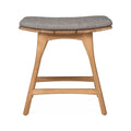 Front view of a coastal backless shower stool in natural teak with tapered legs, two horizontal stretchers and a neutral gray upholstered seat cushion.