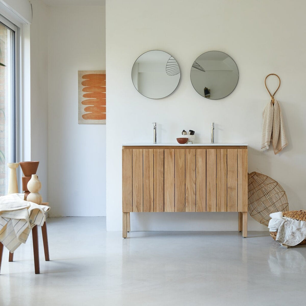 Freestanding modern 48" double-sink bathroom vanity in natural solid wood with vertical slatted cabinet, stone countertop, two chrome faucets and twin round mirrors in a neutral minimalist bathroom setting.
