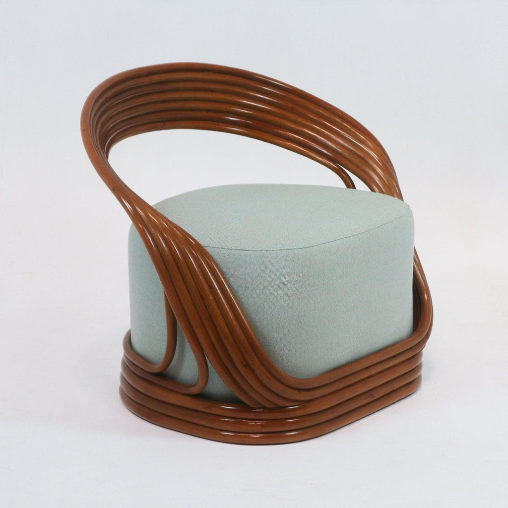 Mid-century modern lounge chair with a glossy brown cane frame that curves around a pale green fabric-upholstered cylindrical seat, featuring layered rattan arms and a wrapped rattan base.