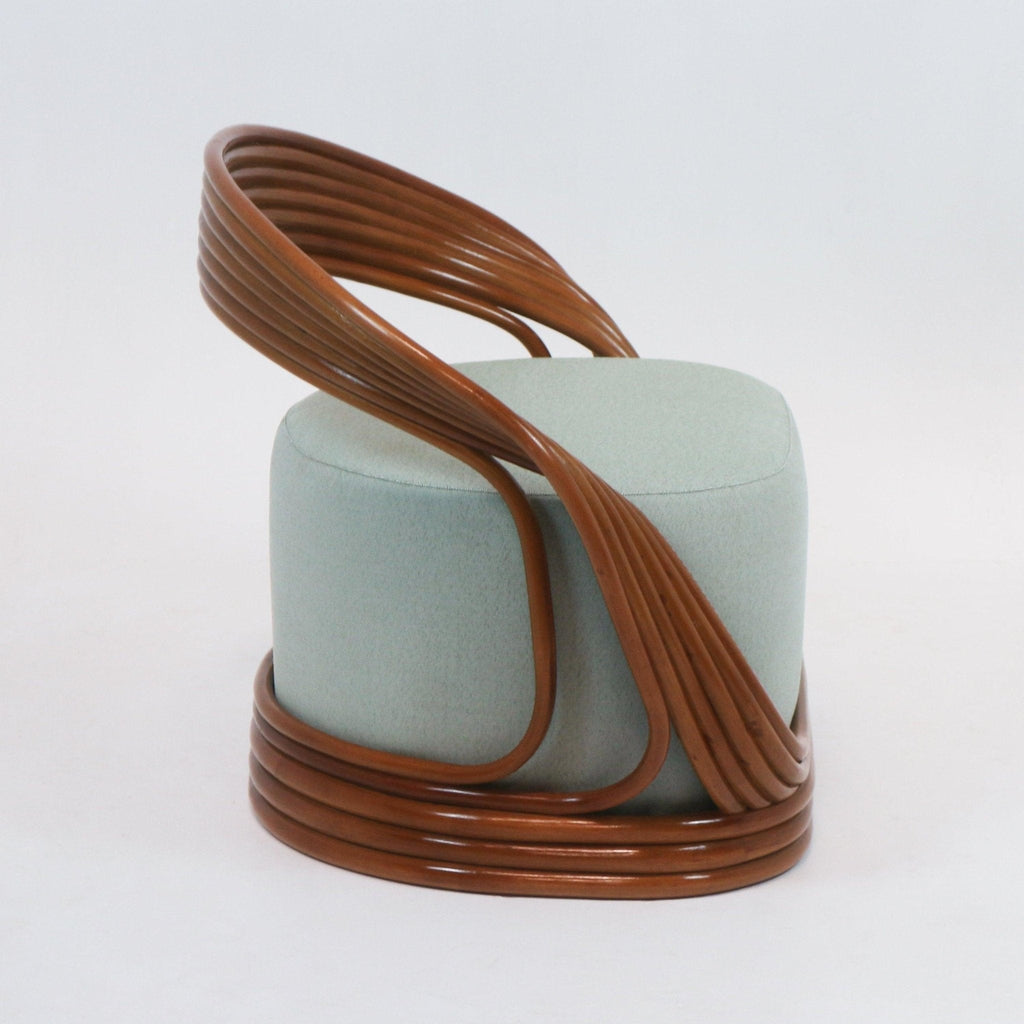 Mid-century modern accent lounge chair with a light green upholstered cylindrical seat wrapped by a continuous brown cane frame that forms a curved back and looped base.