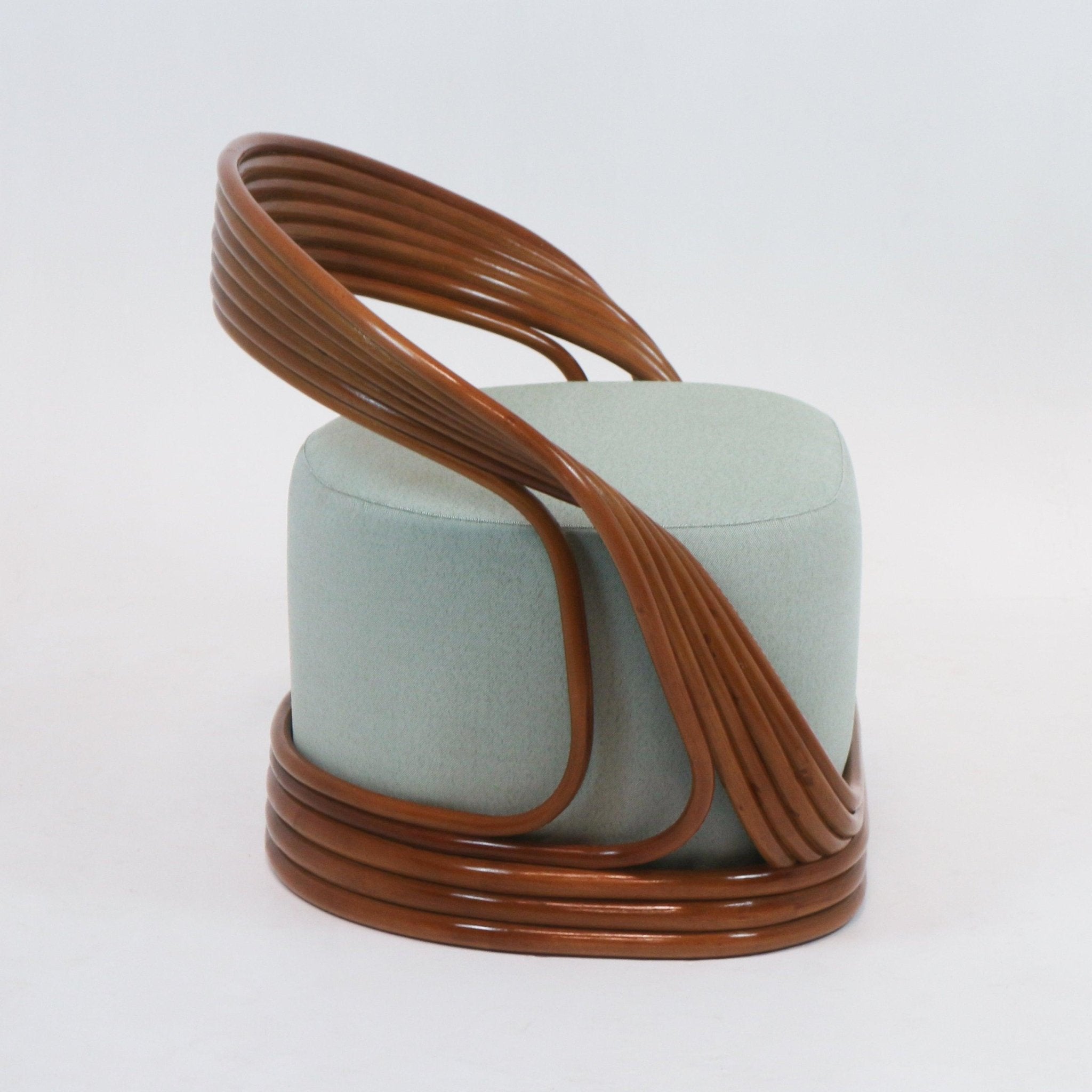 Mid-century modern accent lounge chair with a light green upholstered cylindrical seat wrapped by a continuous brown cane frame that forms a curved back and looped base.