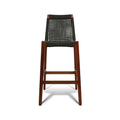 Armless teak outdoor bar stool with solid wood frame and black woven rope seat and open-grid back, tall bar-height legs with integrated footrest.