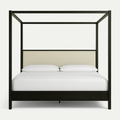 Front-facing modern four-poster bed in mahogany solid wood with a cream upholstered headboard panel, white linens and two pillows set against a plain white background.