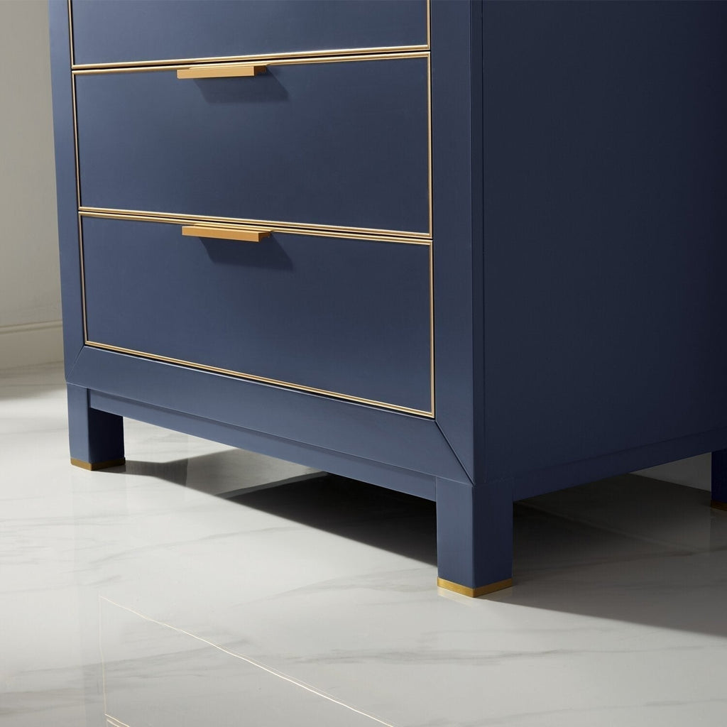 Close-up of the lower corner of a navy-finish solid wood modern bathroom vanity showing gold metal trim, rectangular gold drawer pulls and squared legs with gold caps on a glossy marble-look floor.