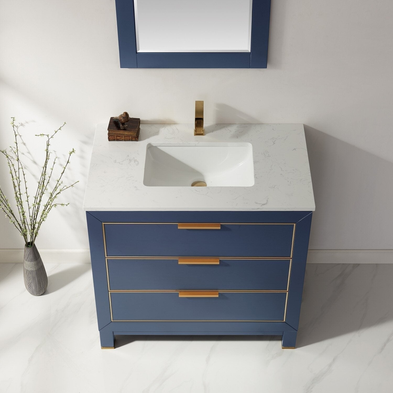 Modern solid wood 36-inch bathroom vanity in navy blue with a white stone countertop, integrated ceramic sink, and brass/gold faucet and drawer hardware with three drawers.
