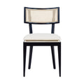 Front view of an armless black solid wood dining chair with a natural rattan cane backrest and a cream upholstered seat cushion, mid-century boho style, on a white background.