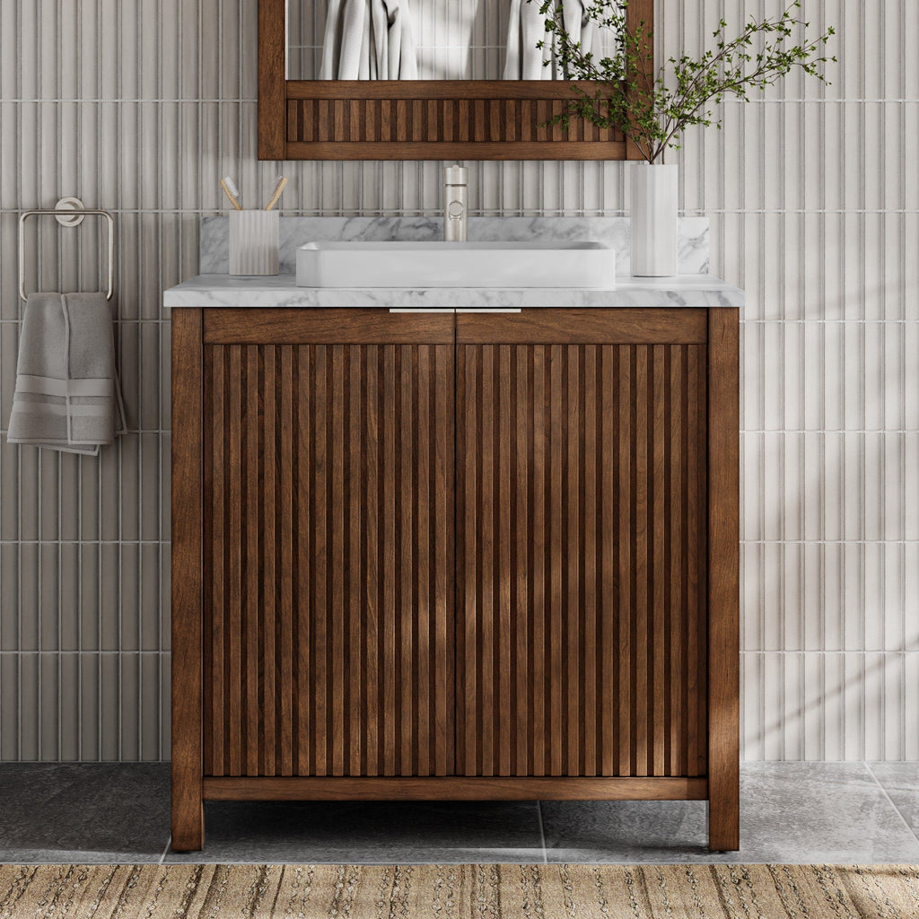 36-inch freestanding fluted solid-wood bathroom vanity in warm brown with a stone marble top, rectangular white vessel sink and single faucet, shown with a matching wood mirror, towel on ring and vase against ribbed tile.