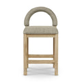 Front view of a counter/bar stool with an arched back and padded beige-taupe boucle seat upholstered in boucle fabric on a natural oak frame with stretcher footrest.