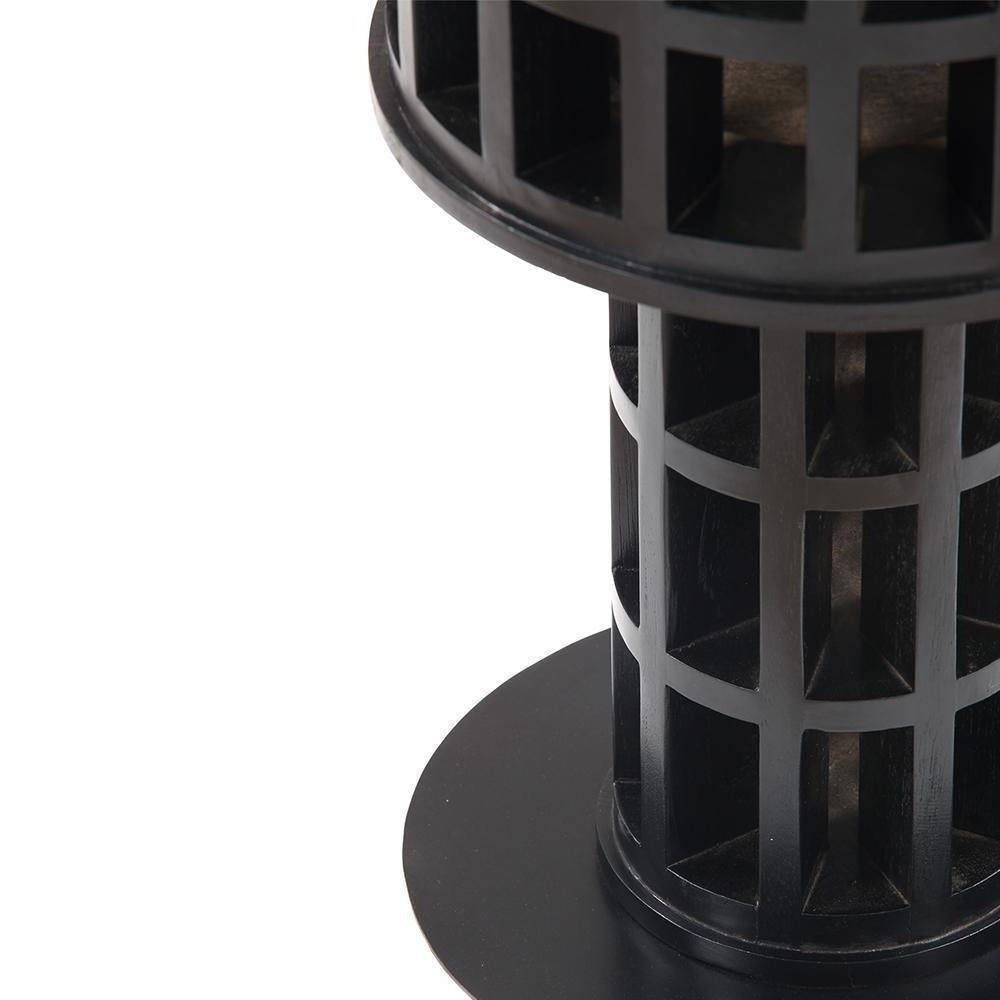 Close-up of a black mahogany side table showing the honeycomb-style solid wood pedestal and round base, highlighting the grid-like cutouts and smooth circular top edge in a modern contemporary finish.