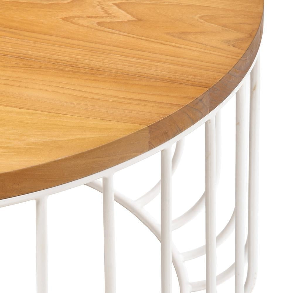 Close-up of a round teak tabletop with warm wood grain and edge detail resting on a white metal wire base with vertical curved iron supports.