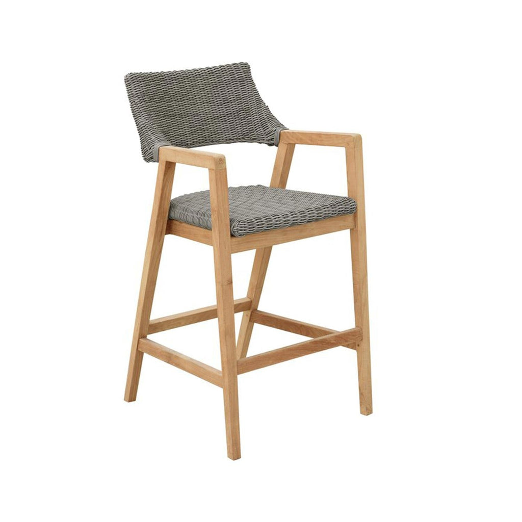 Coastal-style outdoor bar stool with a natural teak frame, gray woven rope seat and back, wooden armrests and a square footrest, designed for kitchen islands or outdoor counters.