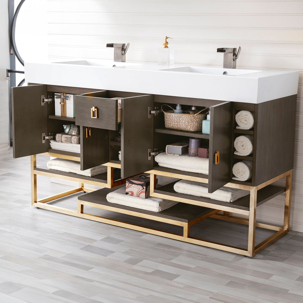 Modern solid-wood bathroom vanity with a white glossy stone composite double-sink top, dark wood cabinet and gold-finish metal base, open shelves and cabinets staged with rolled towels, basket and two metal faucets.