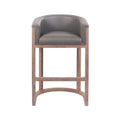 Front view of a mid-century modern teak wood bar stool with a curved taupe faux-leather upholstered seat, low arms, rectangular legs and an arched footrest stretcher.