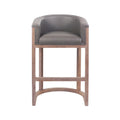 Front view of a mid-century modern teak wood bar stool with a curved taupe faux-leather upholstered seat, low arms, rectangular legs and an arched footrest stretcher.