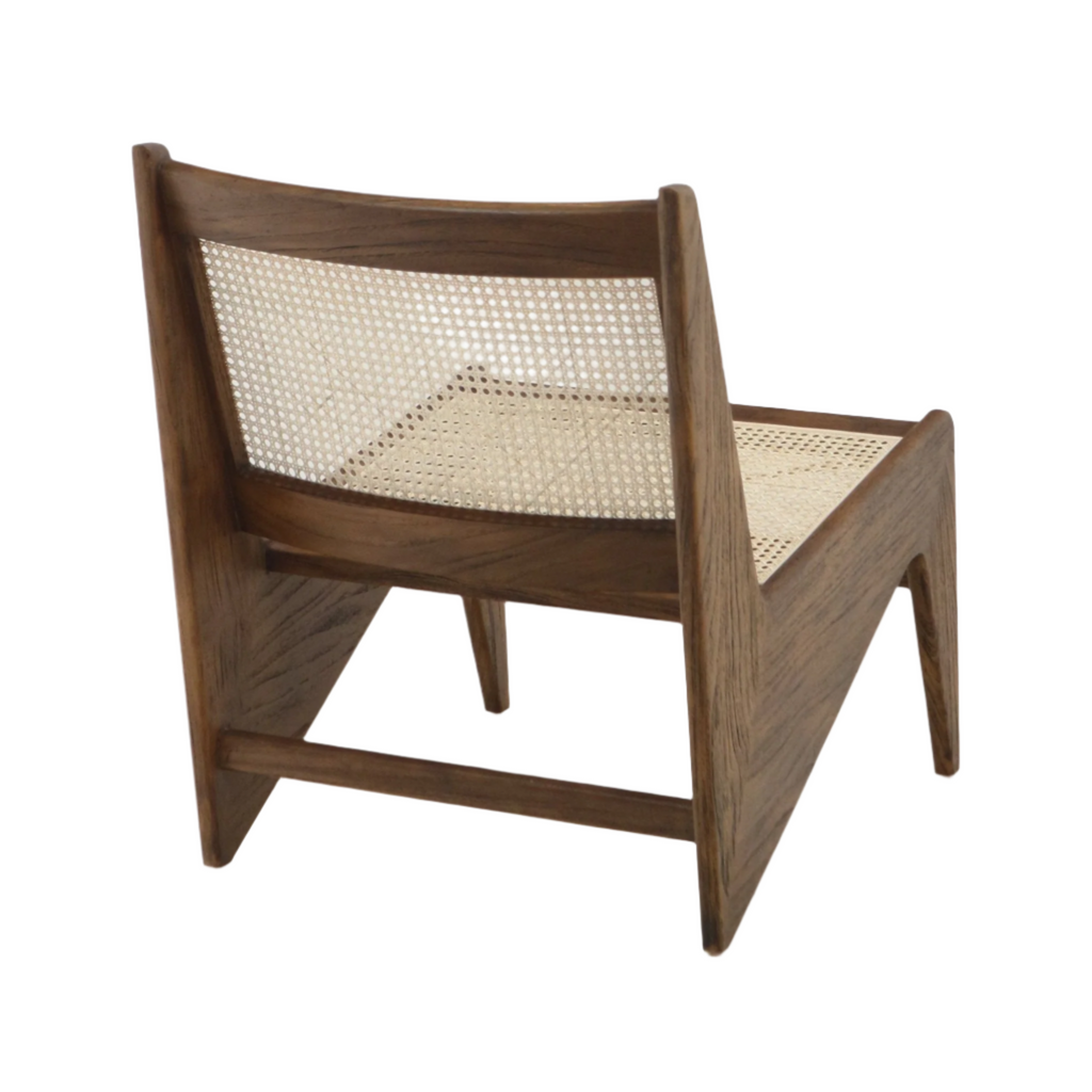 Rear three-quarter view of a mid-century modern low lounge chair in warm teak with solid wood frame and woven natural cane seat and back, armless profile and tapered angled legs.