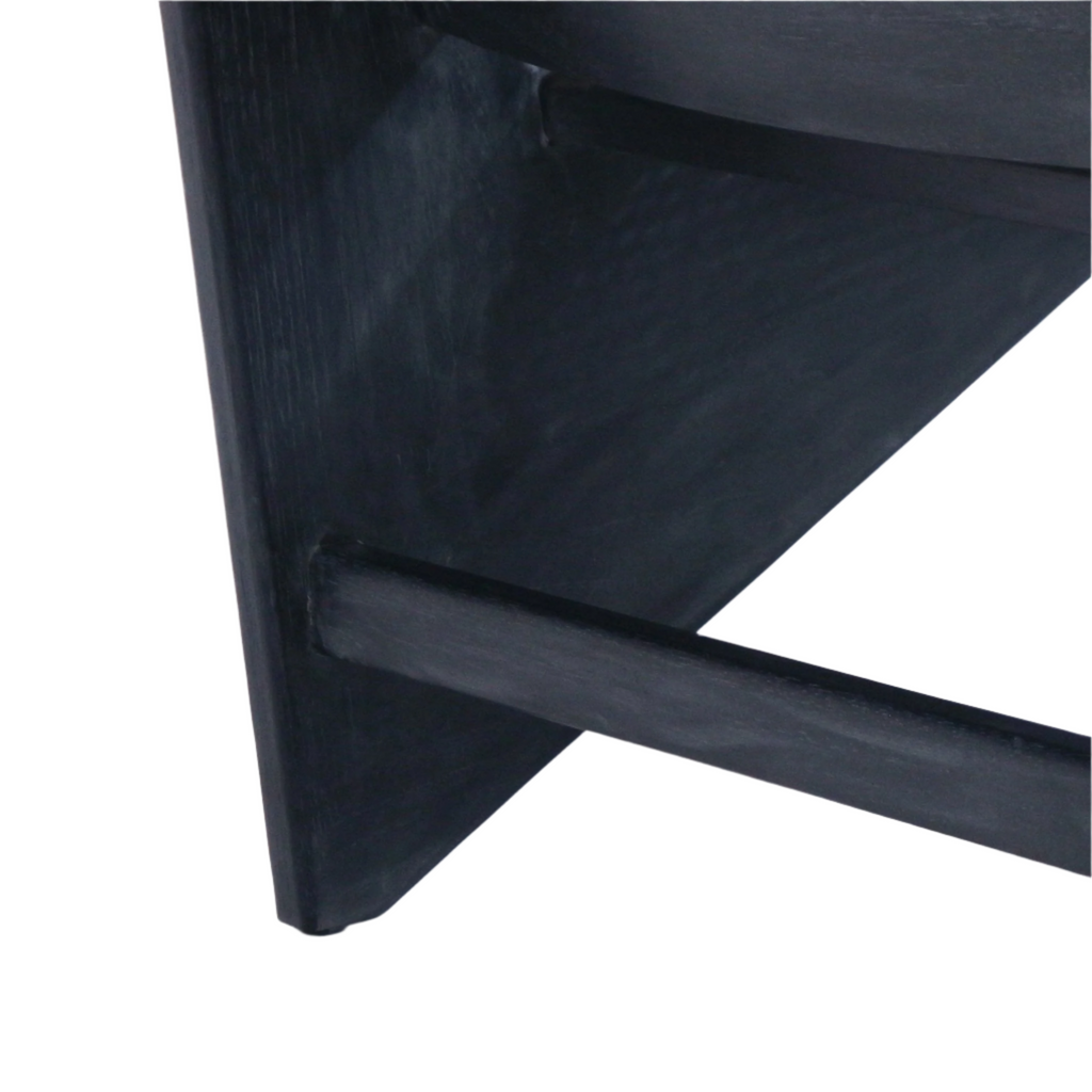 Close-up of a smoked-black stained solid wood triangular leg and round stretcher joint showing subtle wood grain and matte finish on a modern teak accent chair.