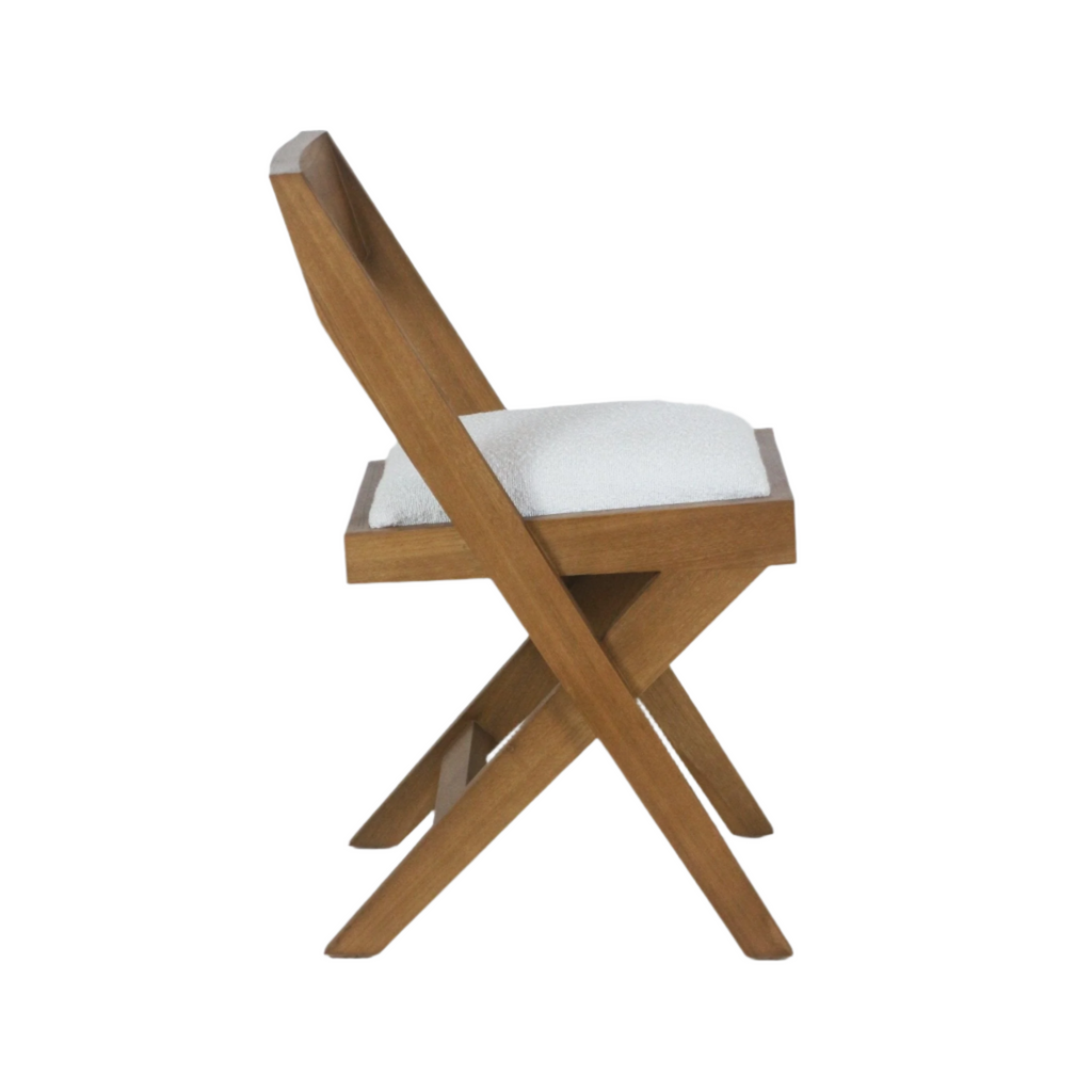 Side profile of a mid-century modern side chair in warm teak wood with crossed X-frame legs and a white boucle upholstered seat cushion and low back.
