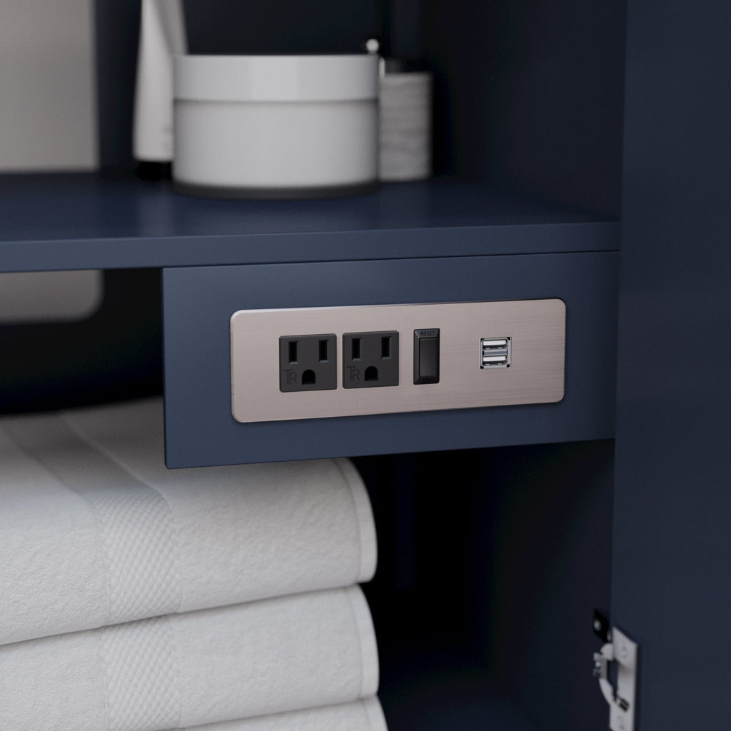 Close-up of a stone-colored solid wood vanity interior showing a brushed-nickel power plate with two electrical outlets, a reset/GFCI switch and dual USB ports above neatly folded white towels.