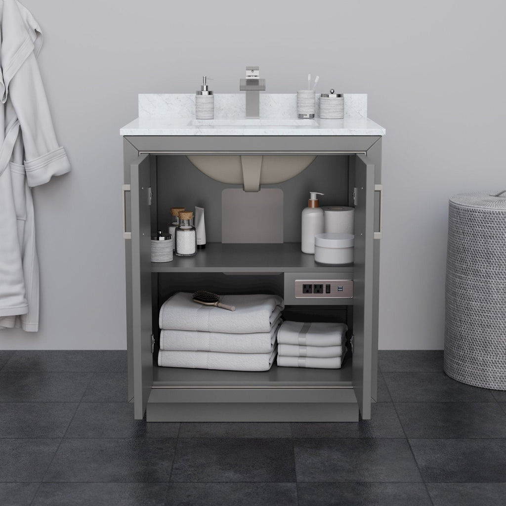 30-inch modern solid wood bathroom vanity in stone finish with a white stone countertop and integrated sink; open doors reveal two shelves with folded white towels, toiletries, a built-in outlet and square chrome faucet.