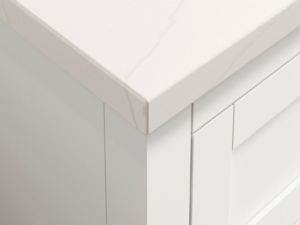 Close-up of a modern bathroom vanity corner featuring a light stone countertop with subtle veining and white solid wood drawer fronts, showing the mitered countertop edge and clean contemporary lines.