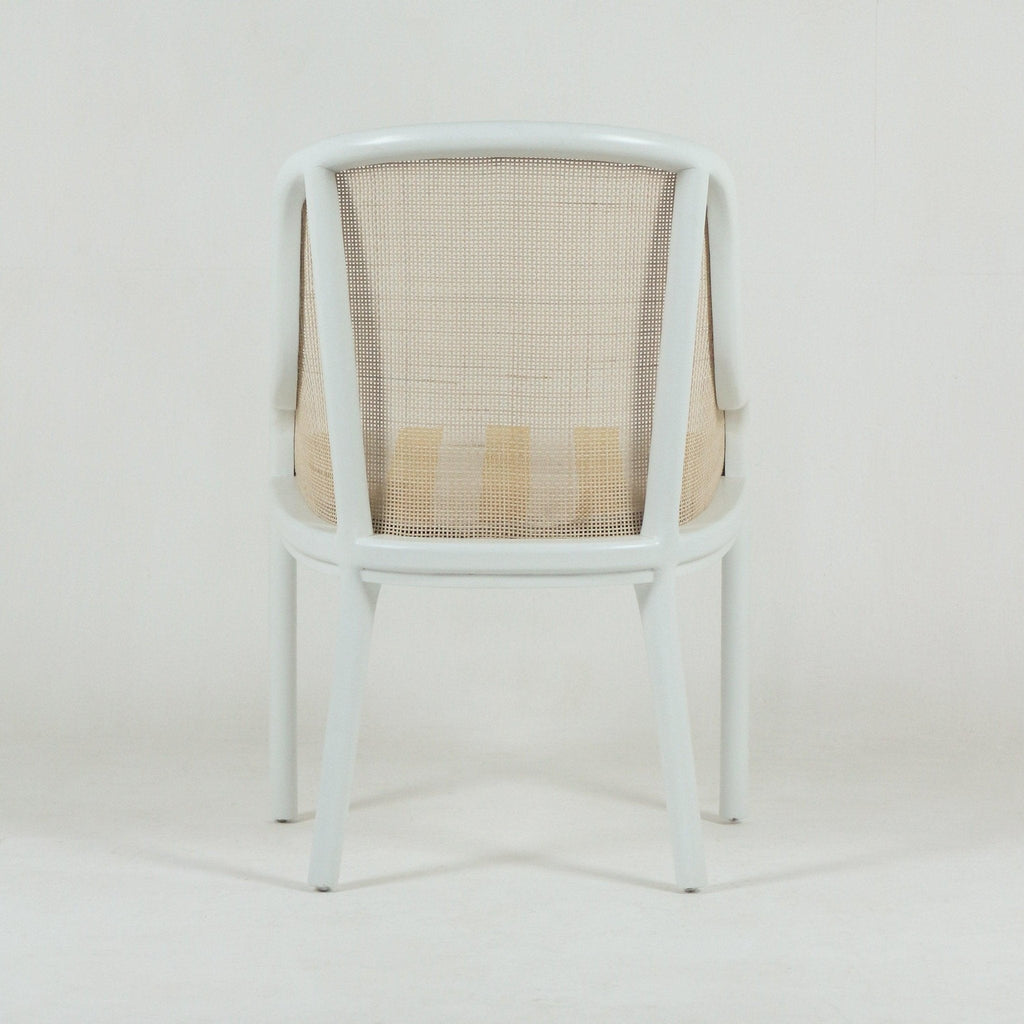 Rear view of a bentwood dining chair with a white painted wood frame and beige woven cane backrest and seat, featuring a curved top rail and tapered legs on a plain white background.