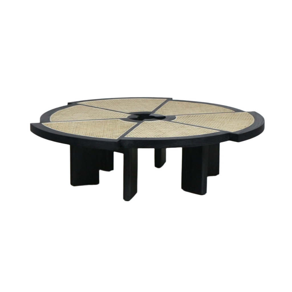 Low round coffee table with a black wooden frame and six natural cane inlaid wedge panels radiating from a small central opening, supported by chunky black block legs in a modern midcentury style.