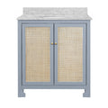 Front view of a freestanding single-sink bathroom vanity with a matte light-blue solid wood frame, woven cane cabinet doors, small brass knobs and a Carrara marble top with oval undermount sink.