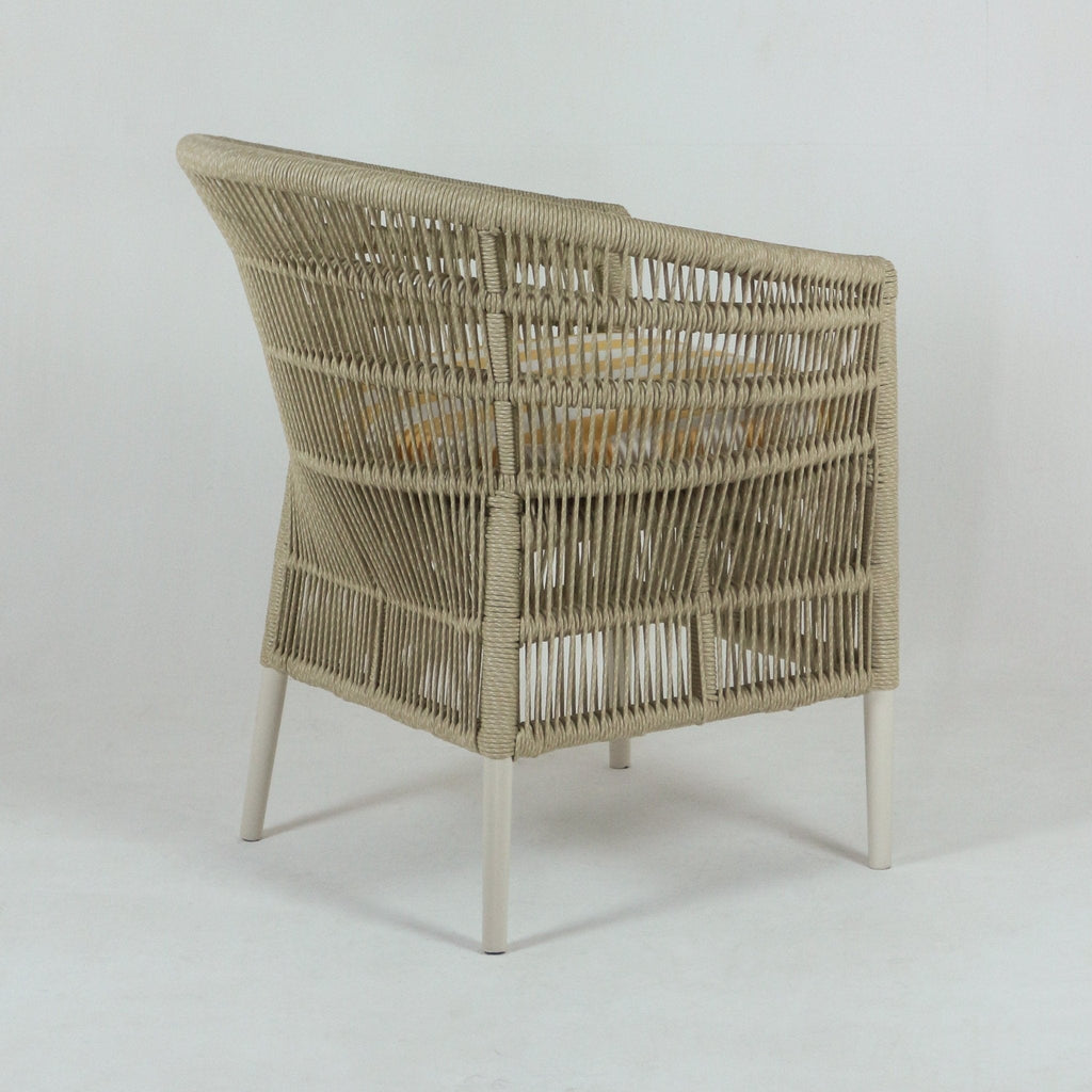 Back three-quarter view of a coastal outdoor patio armchair with a beige rope-wrapped frame, white metal legs and a cushioned seat covered in light yellow striped fabric.