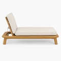 Low-profile outdoor sun lounger with a solid teak wood frame and cream fabric cushions, shown with the adjustable backrest raised in a minimalist coastal-modern silhouette.