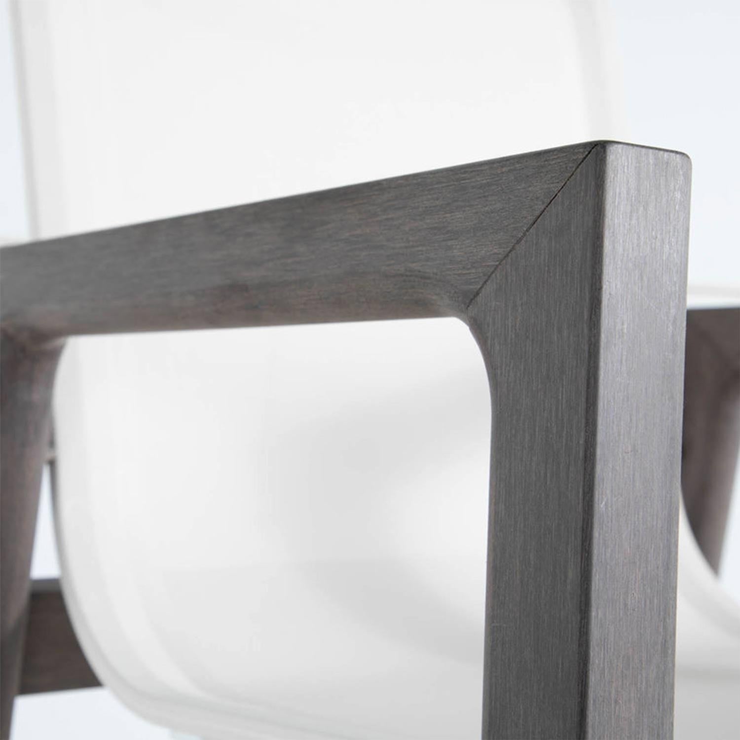 Close-up of a teak armrest and corner joint on an outdoor bar stool, showing warm natural teak wood grain with a curved white molded seat visible in the background.