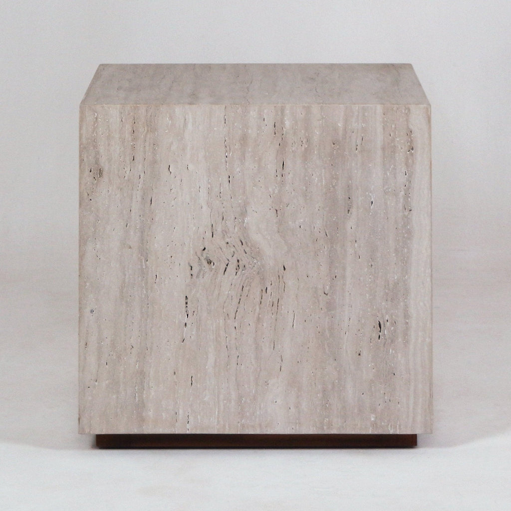 Front view of a modern cube-shaped nightstand made from natural beige travertine with subtle vertical veining, sitting on a slim wood base.