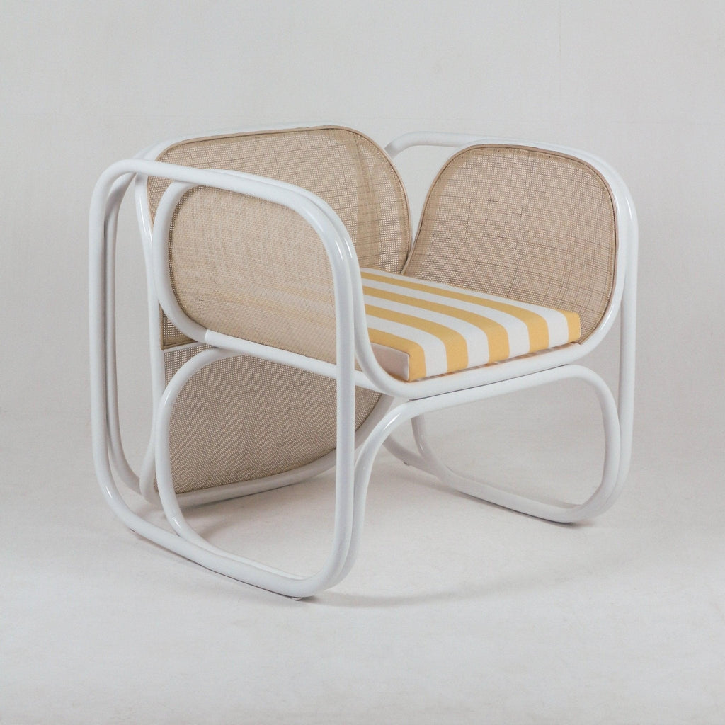 Modern lounge chair with a white metal frame, natural cane back and sides, and a yellow-and-white striped fabric seat cushion shown on a neutral studio background.