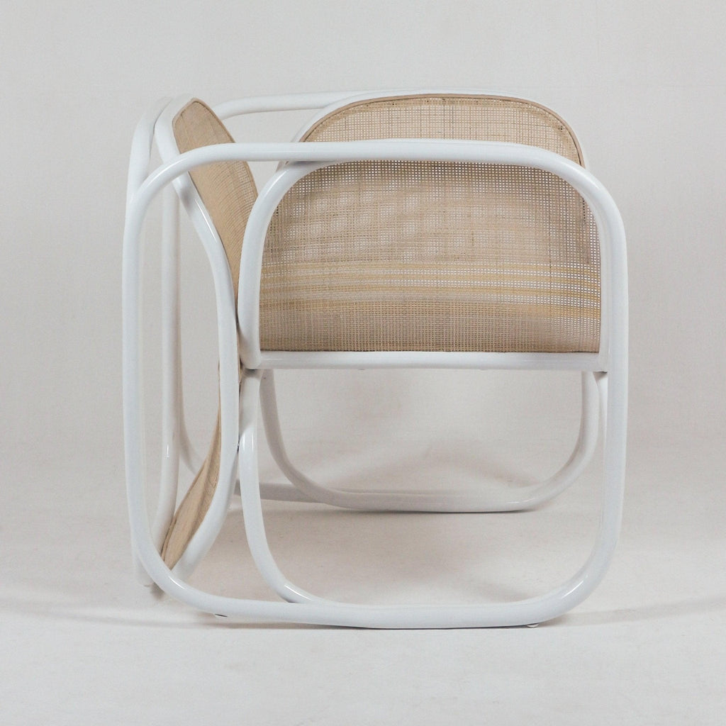 Side view of a modern lounge chair with a curved white metal tubular frame, integrated arms and natural woven cane seat and back, photographed on a neutral background.