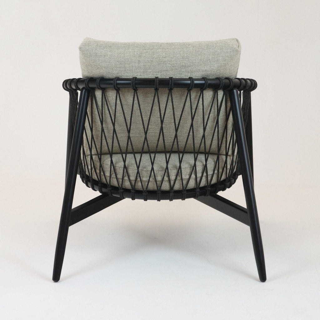 Rear view of a modern lounge chair with beige alpaca boucle cushions, black solid wood legs and a rope-woven back in a diamond lattice pattern.