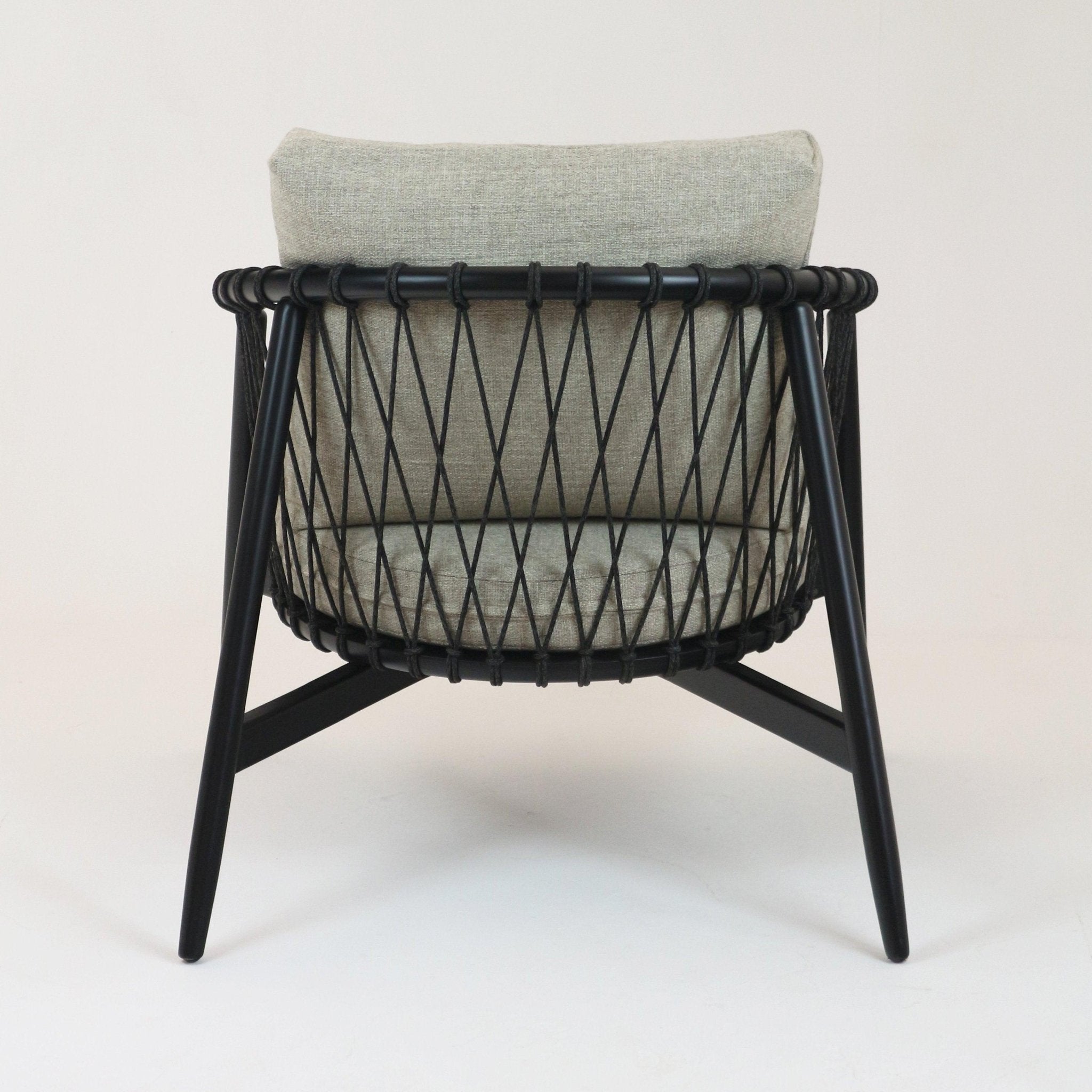 Rear view of a modern lounge chair with beige alpaca boucle cushions, black solid wood legs and a rope-woven back in a diamond lattice pattern.