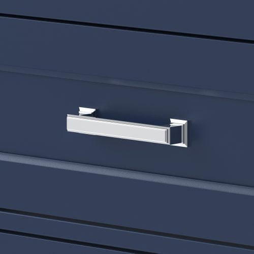 Close-up of a chrome rectangular drawer pull mounted on a deep blue solid wood vanity drawer front with subtle horizontal grooves, reflecting light and reinforcing a glam bathroom aesthetic.
