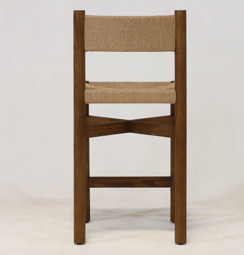 Front view of a walnut wood counter stool with a natural papercord woven seat and back, armless modern-coastal frame and X-shaped stretcher footrest shown on a plain light background.