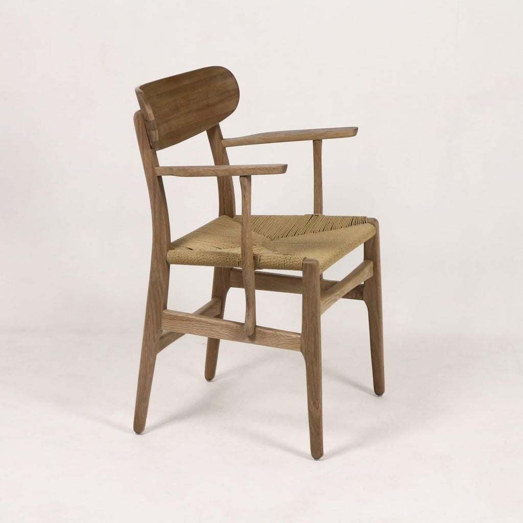 Side view of a Scandinavian-style solid wood dining armchair with a curved wooden backrest, slender tapered legs and a woven natural rope seat in a light brown oak finish.