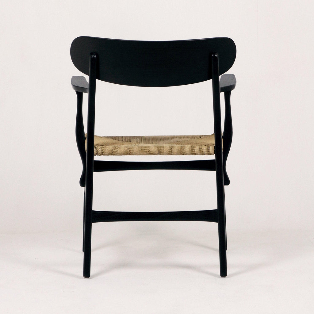 Rear view of a black solid wood accent dining chair with a curved backrest, sculpted arms and a natural woven rope seat shown against a plain white background.