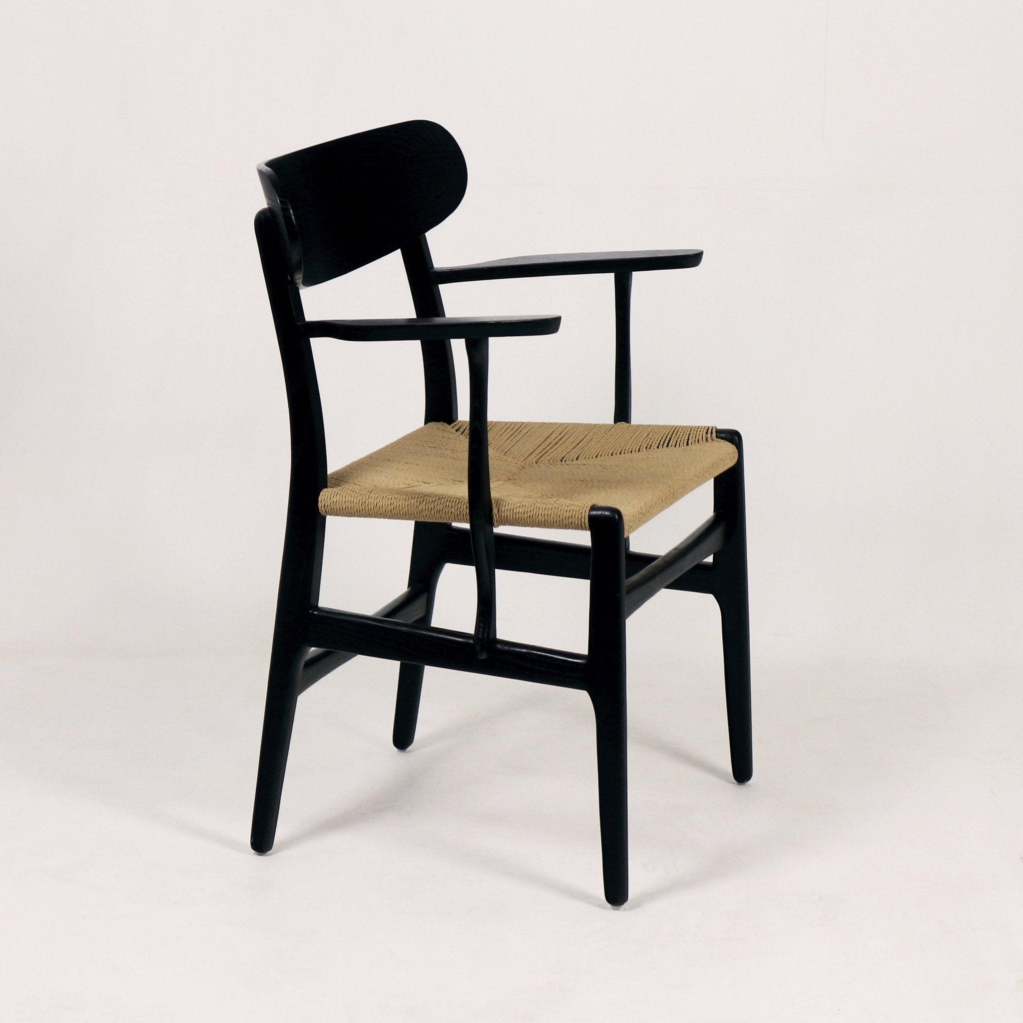Black solid-wood accent dining chair with curved back and slim arms, featuring a natural woven rope seat and tapered legs in a mid-century Scandinavian modern style.