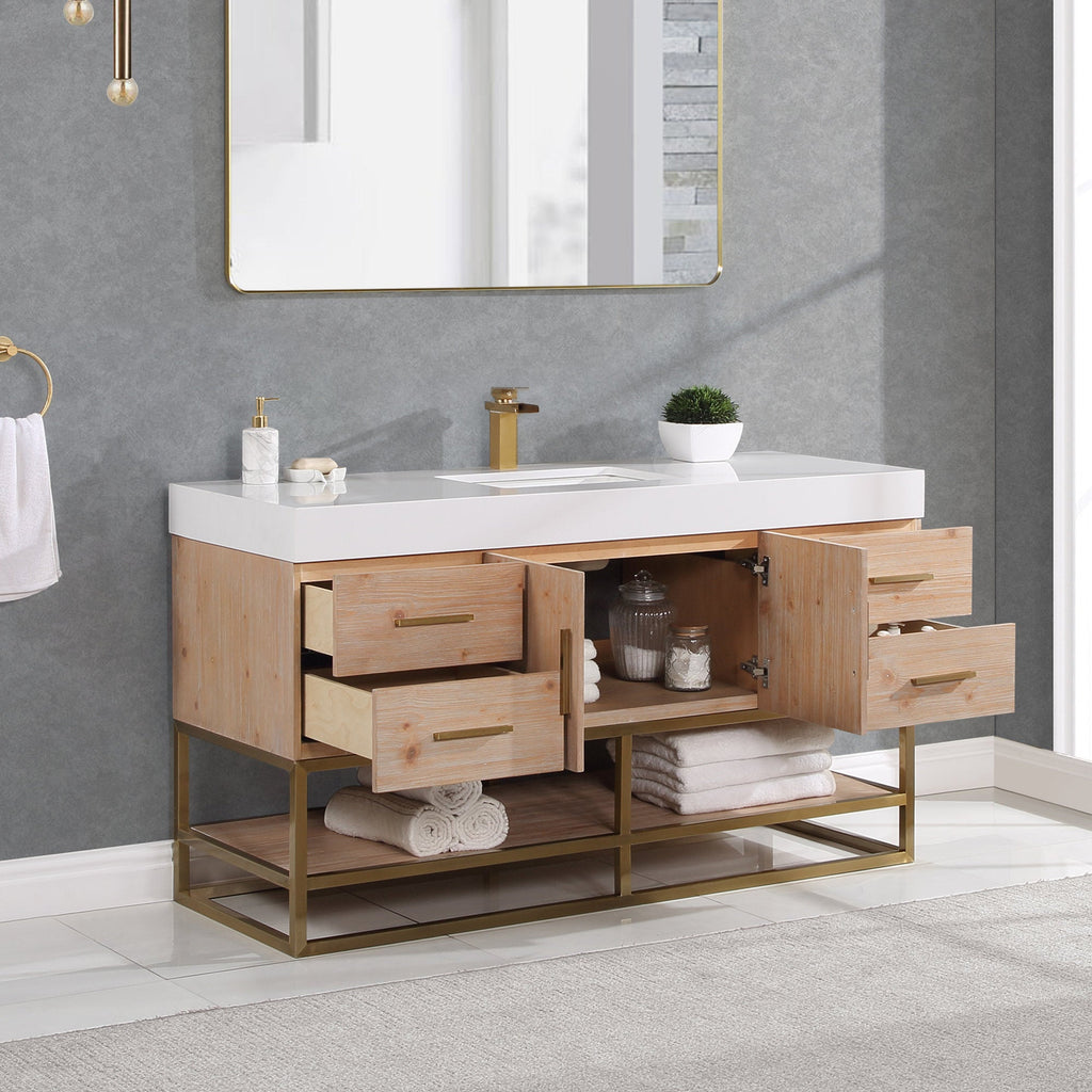 Modern 60-inch single-sink bathroom vanity with a white composite stone top and rectangular undermount sink, natural wood cabinet with brass hardware, open drawers and gold metal base shelf holding towels and jars.